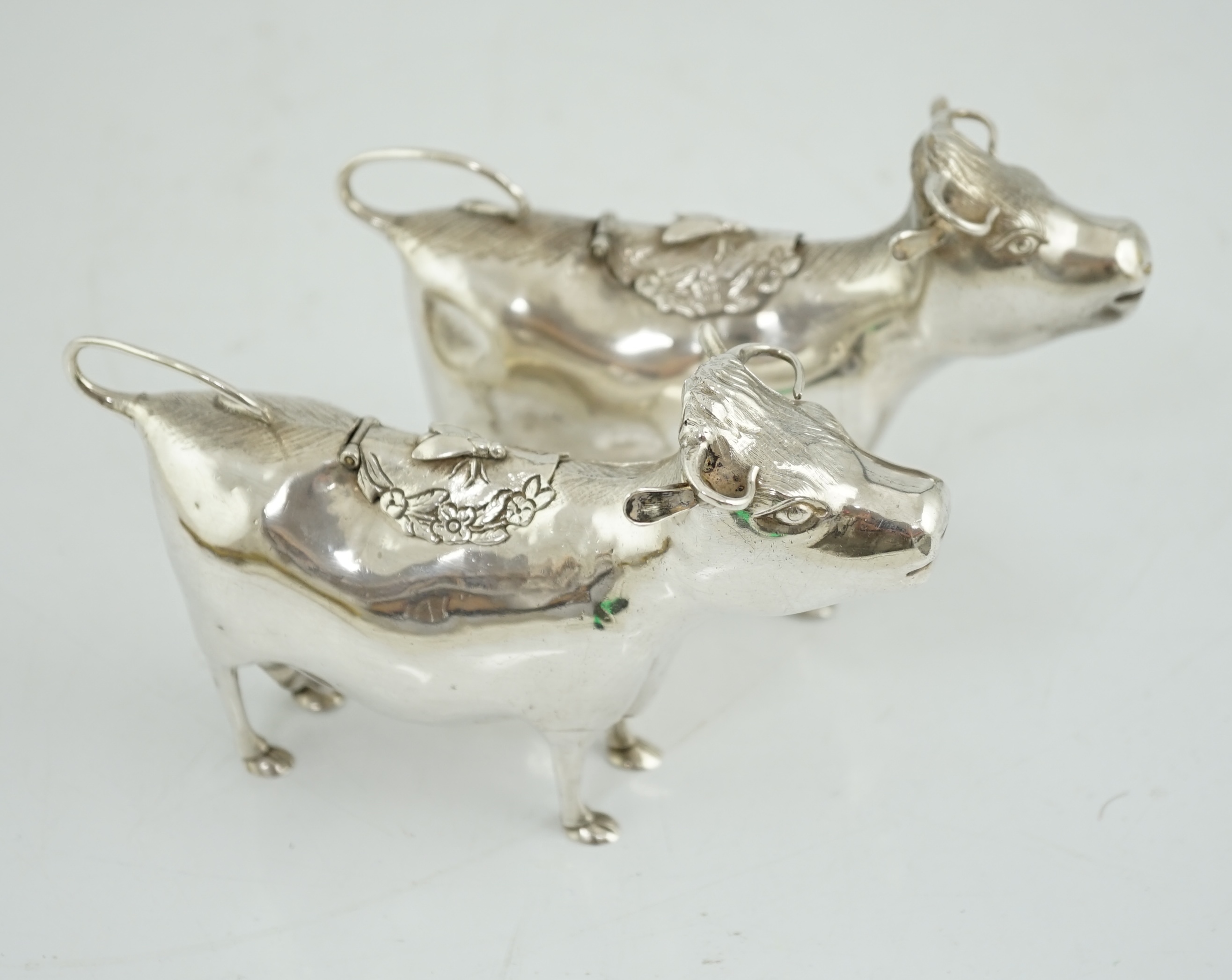 A pair of Elizabeth II silver cow creamers, by Heming & Co